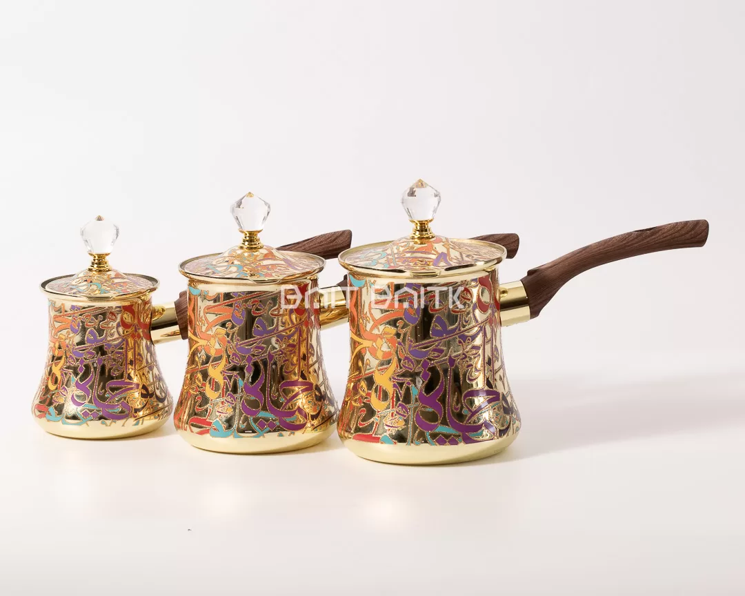 Front view of three gold Turkish coffee pots in different sizes with Arabic calligraphy design and crystal knobs