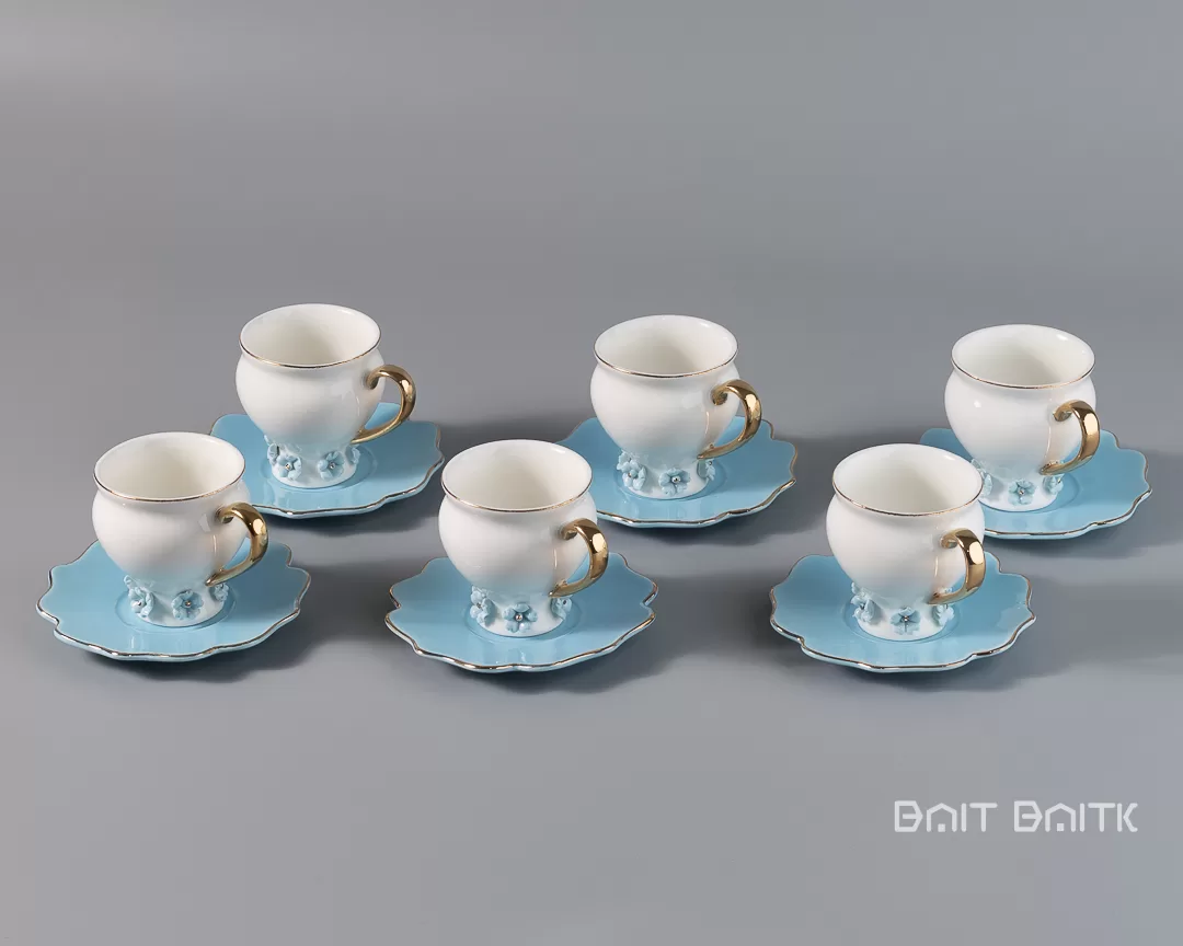 Six blue porcelain coffee cups with matching saucers arranged on a grey background