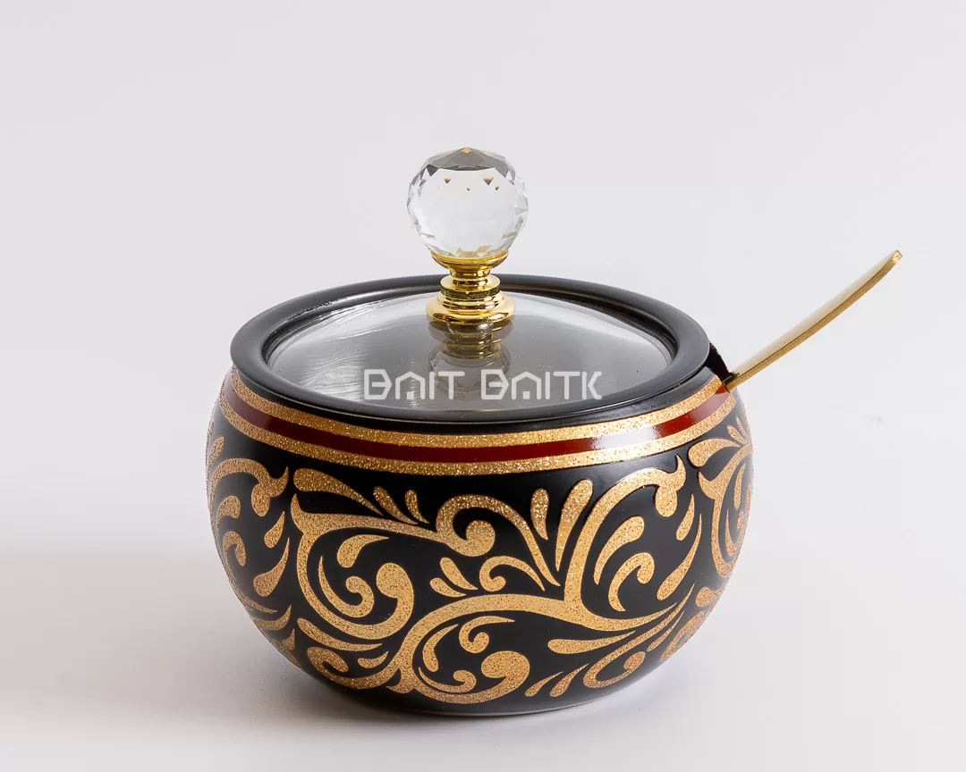 "Black sugar jar with gold ornamental patterns, red accent line, crystal knob, and gold spoon — luxurious decorative jar from Bait Baitk."